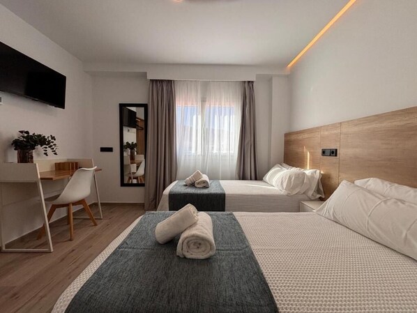 A modern hotel room with two beds, a desk, and a TV. - Hostal Hs Puerto Lumbreras (Puerto Lumbreras)