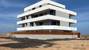 A modern multi-story building with a flat roof, large windows, and a wooden facade.