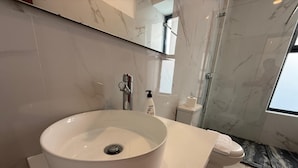 A bathroom with a large white sink, a toilet, and a shower area.