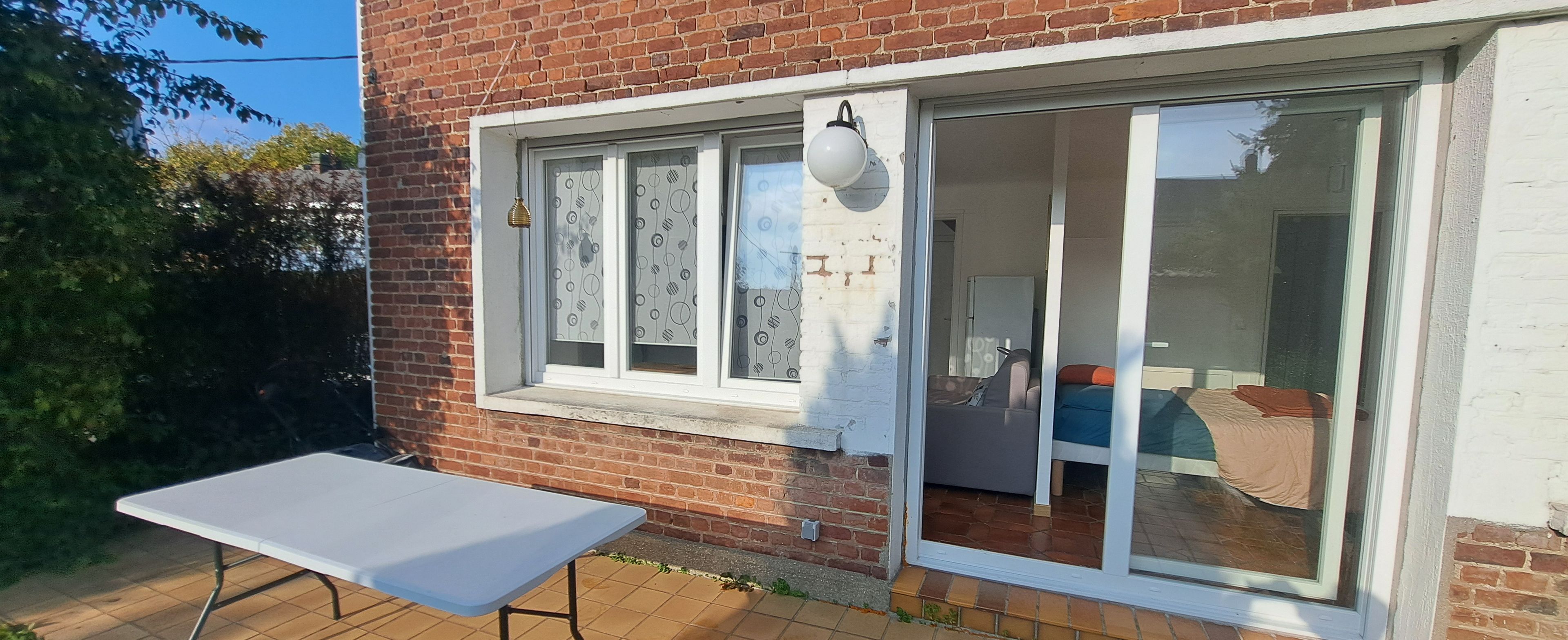A brick house with a sliding glass door leading to a living area.