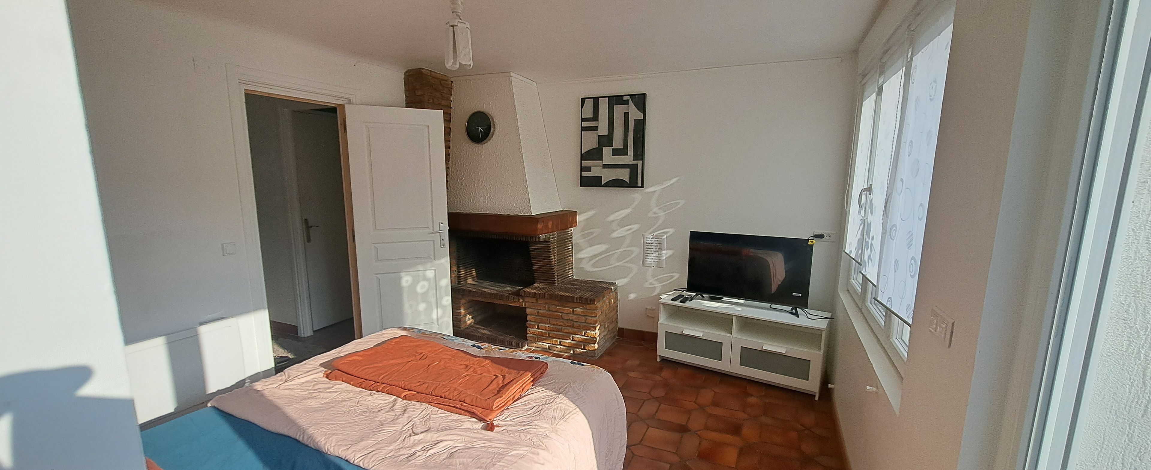 Une chambre à coucher avec un lit, une télévision, une cheminée et une porte.