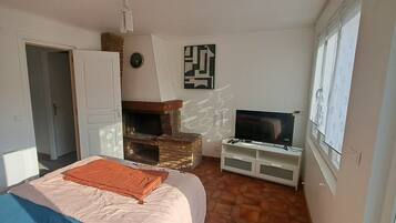 Une chambre à coucher avec un lit, une télévision, une cheminée et une porte.