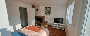 Une chambre à coucher avec un lit, une télévision, une cheminée et une porte.