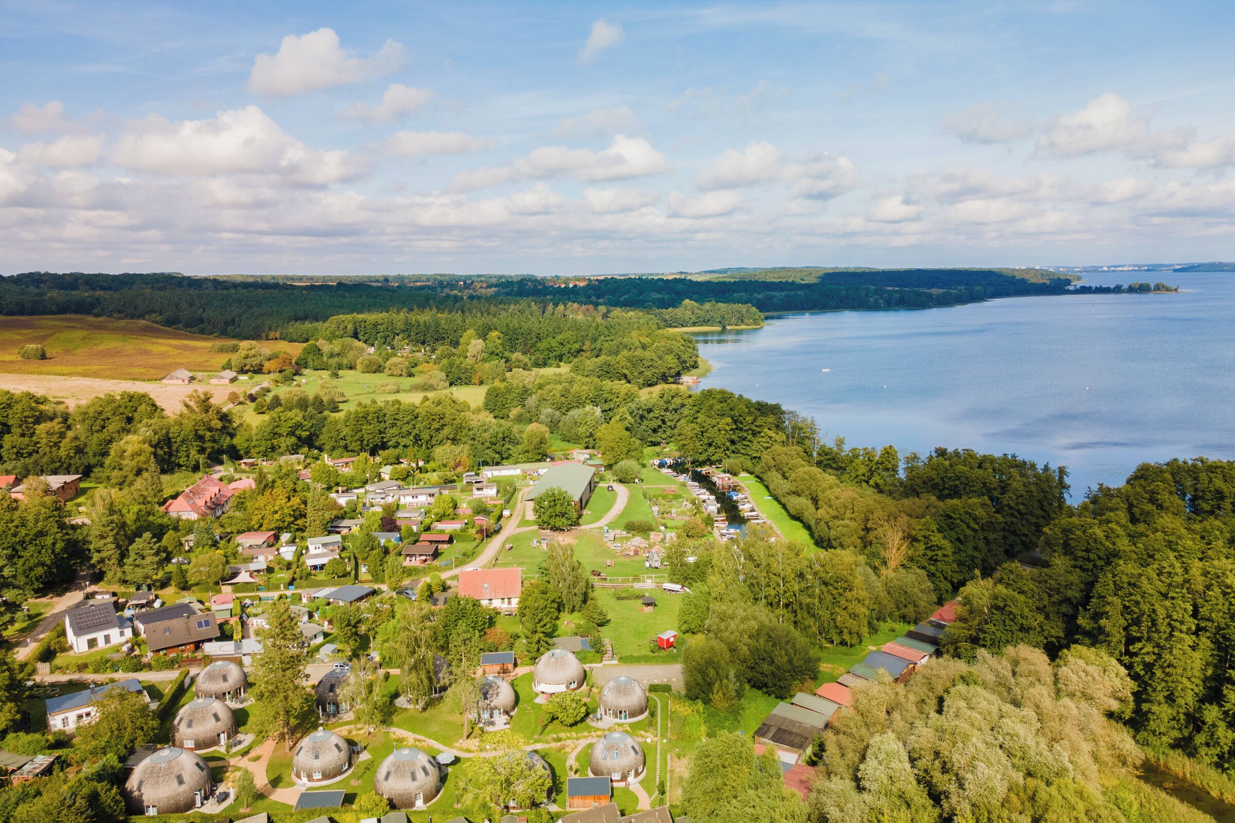 An aerial view of a residential area with houses, a lake, and a forested area.