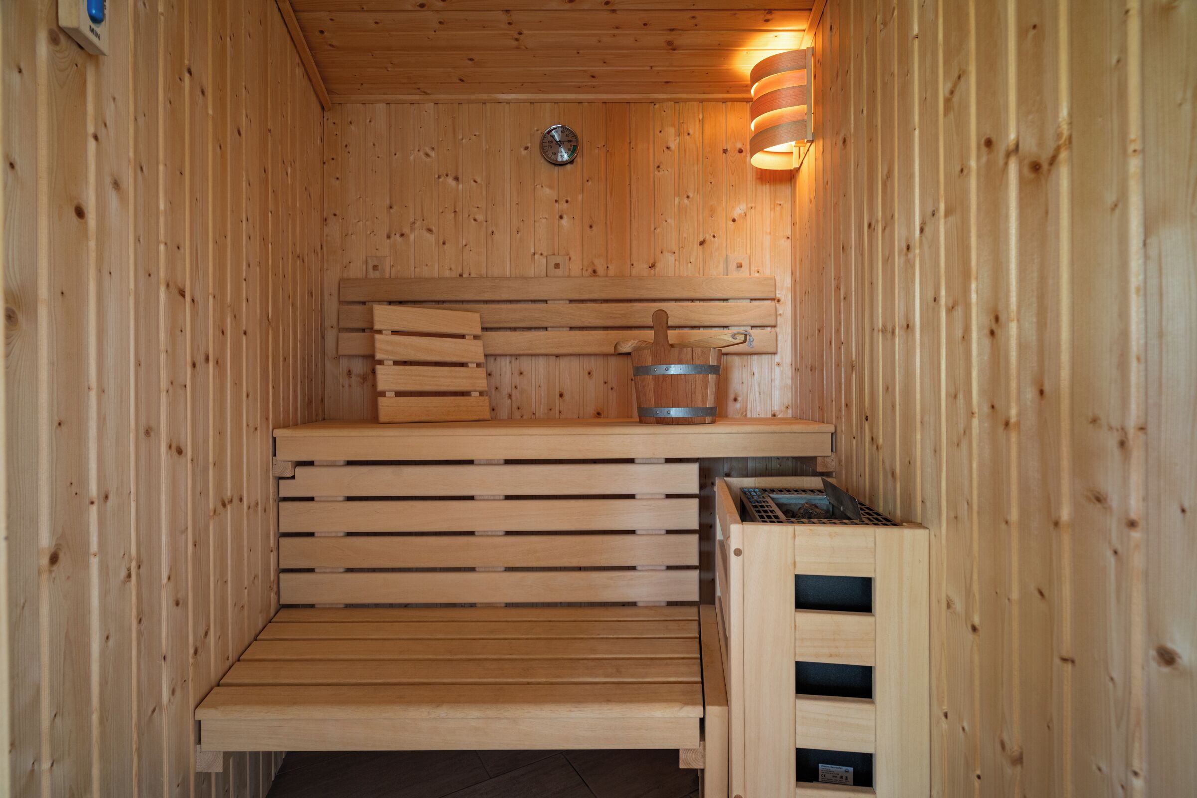 A wooden sauna with benches and a steam shower.