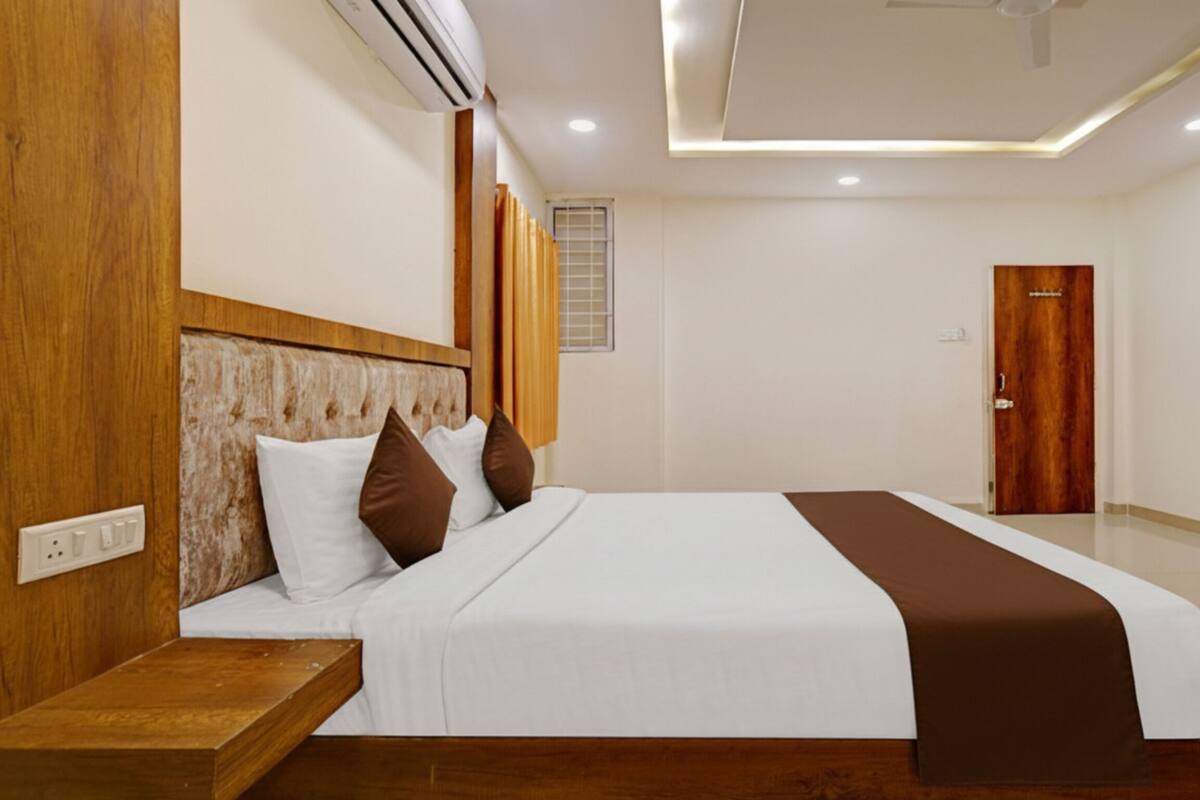 Une chambre d’hôtel moderne avec un grand lit, une tête de lit en bois et une table de chevet.