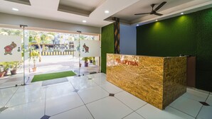 Un espace d’accueil doté d’un comptoir en marbre, d’un ventilateur de plafond et de plantes en pot.