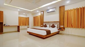 Une chambre d’hôtel avec un grand lit, une tête de lit en bois et des rideaux.