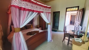 A bedroom with a canopy bed, a wooden dresser, and a desk with a telephone. - IHURU 50 HOTEL AND GARDENS (Kasese)