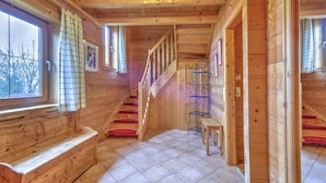 A wooden interior with a staircase, a bench, and a window with a curtain. - Scenic Stay in Feriendorf Wildschonau Chalet (Wildschönau)