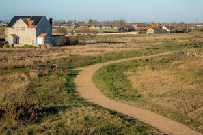 A rural landscape with a gravel path leading to a house with solar panels. - Snowdrop Lodge Dog Friendly Nr Anderby Creek (Alford)