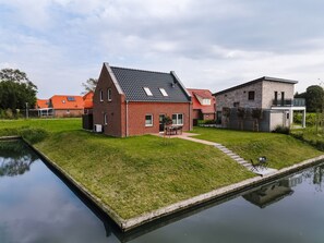 Il s’agit d’une propriété résidentielle comprenant un étang, une maison en briques et un bâtiment moderne doté d’un balcon.
