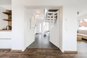 Une cuisine moderne avec des meubles blancs, un plan de travail en bois et une étagère intégrée.