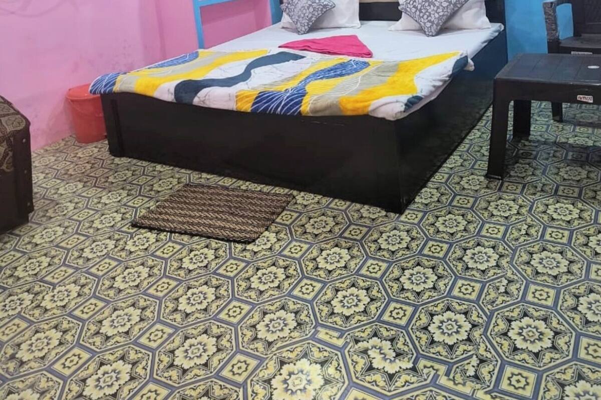 Un dormitorio con cama, ventilador de techo, ventana con aire acondicionado y suelo estampado.