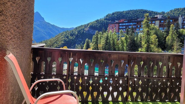 A balcony with a view of a mountainous landscape and a building in the background.