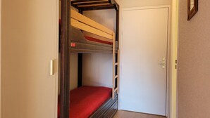 A room with a bunk bed, a door, and a small window.