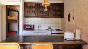 A compact kitchen with wooden cabinets, a microwave, a sink, and a coffee maker.