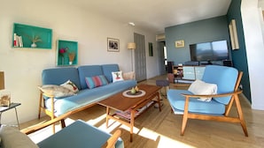 Un salon avec un canapé, des fauteuils, une table basse et un téléviseur.