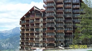 A multi-story hotel with balconies, set against a mountainous backdrop. - Renovated studio for 4, valley view, near slopes (Pra-Loup)