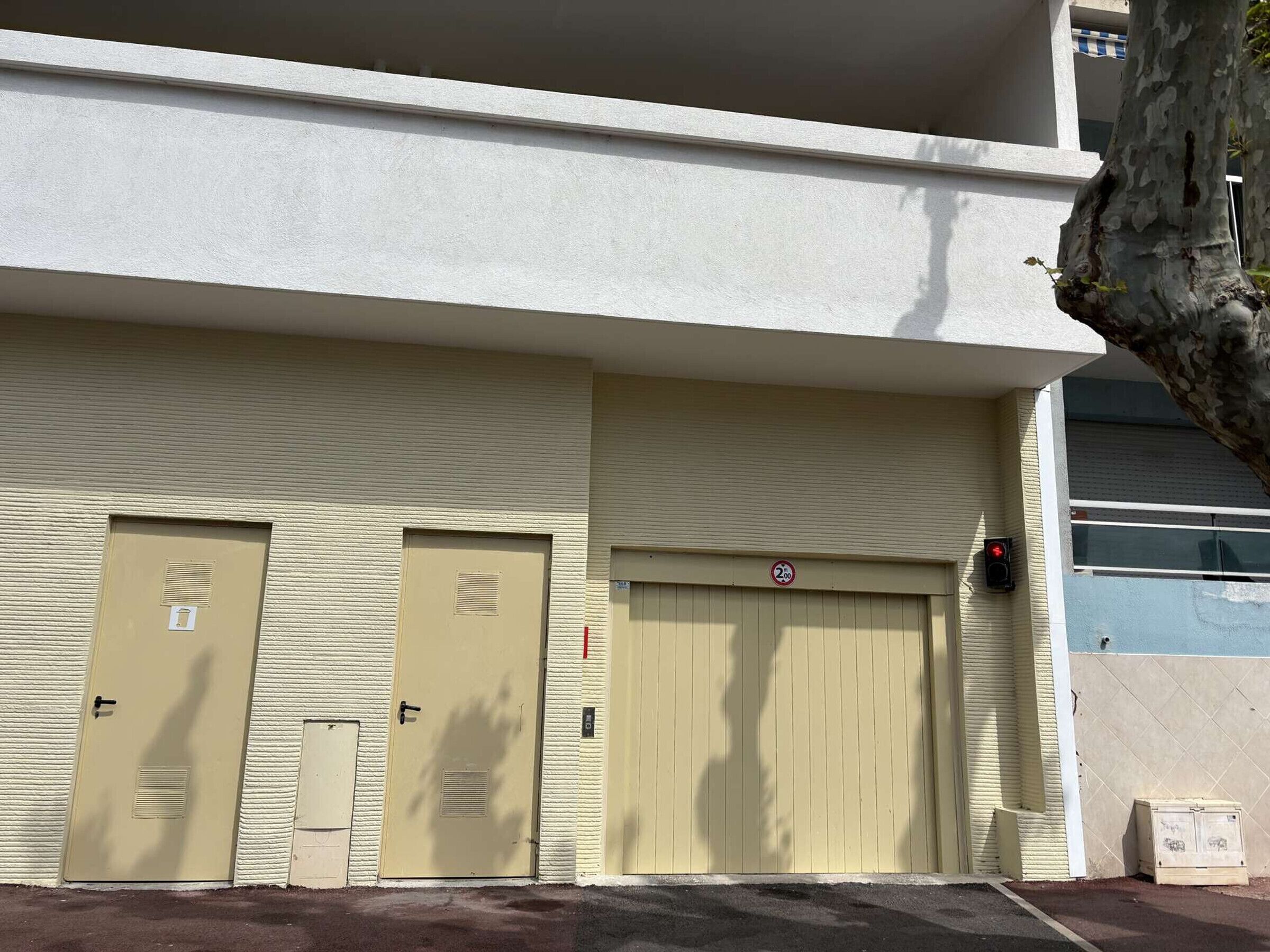 A building with three beige doors, a no parking sign, and a red traffic light.