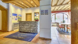 A reception area with a stone counter, a blue welcome mat, and a wooden ceiling. - Wildschonau Alpine Vicky Apartment (Wildschönau)