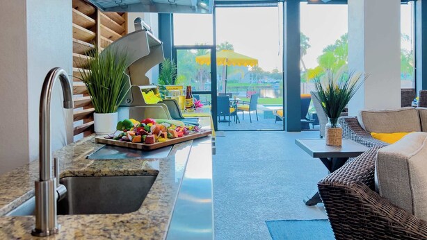 Una cucina moderna con lavello in acciaio inossidabile e un'area pranzo con mobili in vimini e vista sull'esterno.