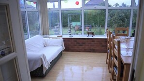 A room with a bed, a dining table with chairs, and a view of a garden through large windows. - Great base for a Yorkshire adventure (Malton)