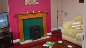 A living room with a fireplace, a sofa, a coffee table, and a television. - Great base for a Yorkshire adventure (Malton)