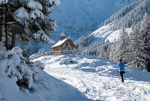 A snow-covered mountain path leading to a wooden cabin with a bell tower, surrounded by snow-laden trees. - Holiday Village Wildschonau Chalet With Terrace (Wildschönau)