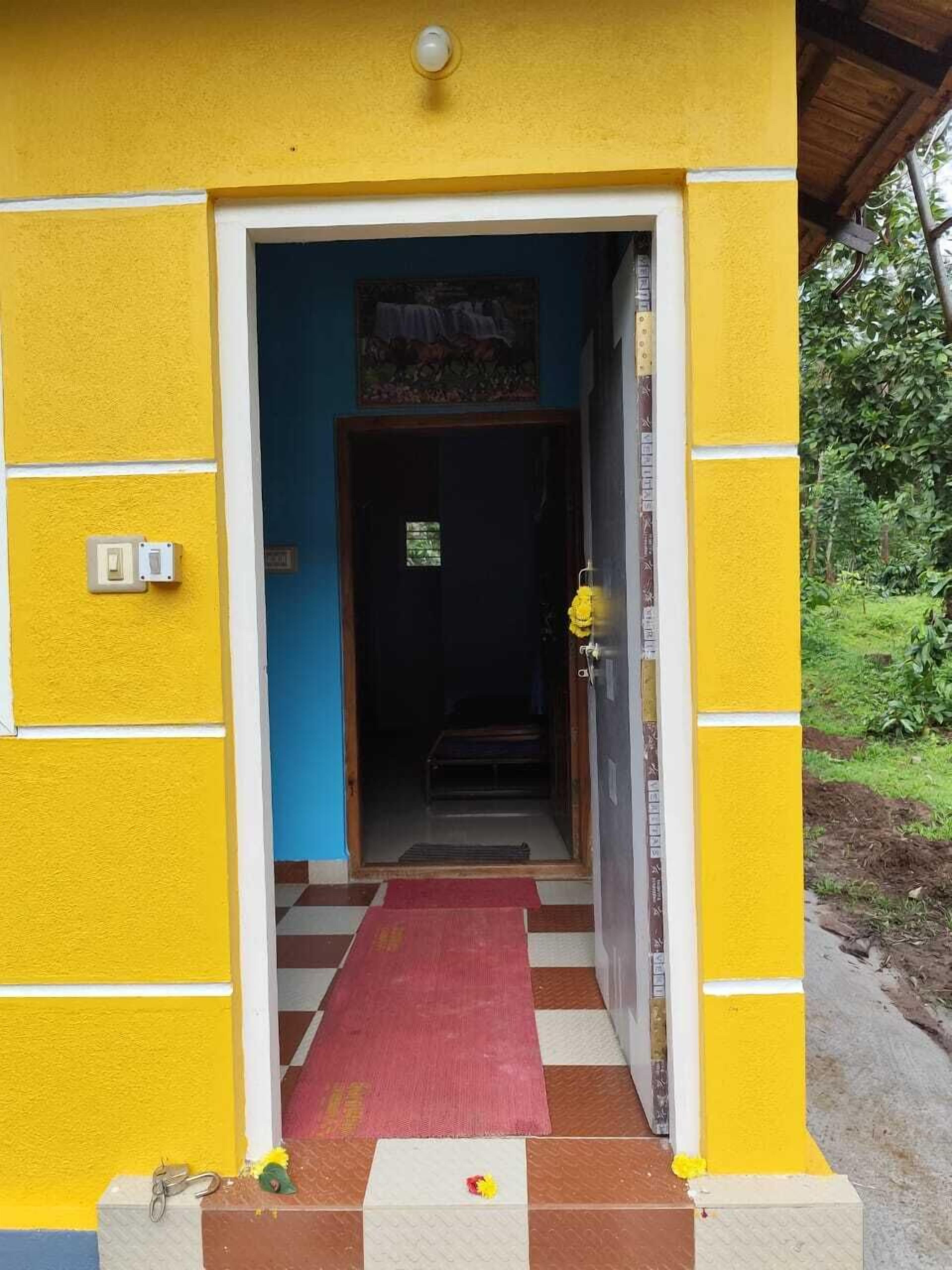 A yellow building with a red mat leading to a dark interior.