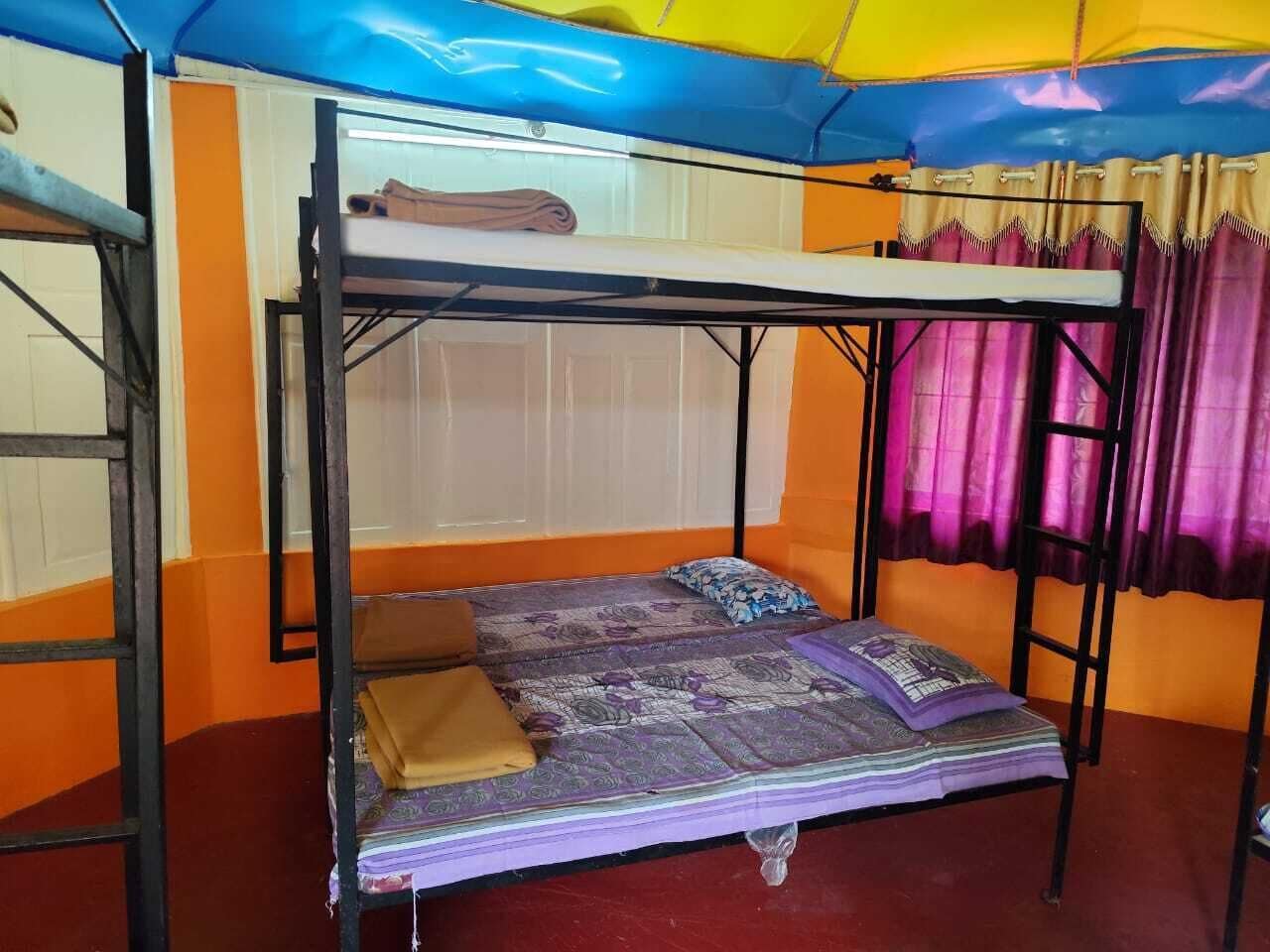 Un lit superposé avec un matelas et des oreillers, une échelle et un rideau.