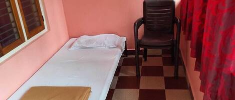 A small room with a single bed, a chair, and a window.