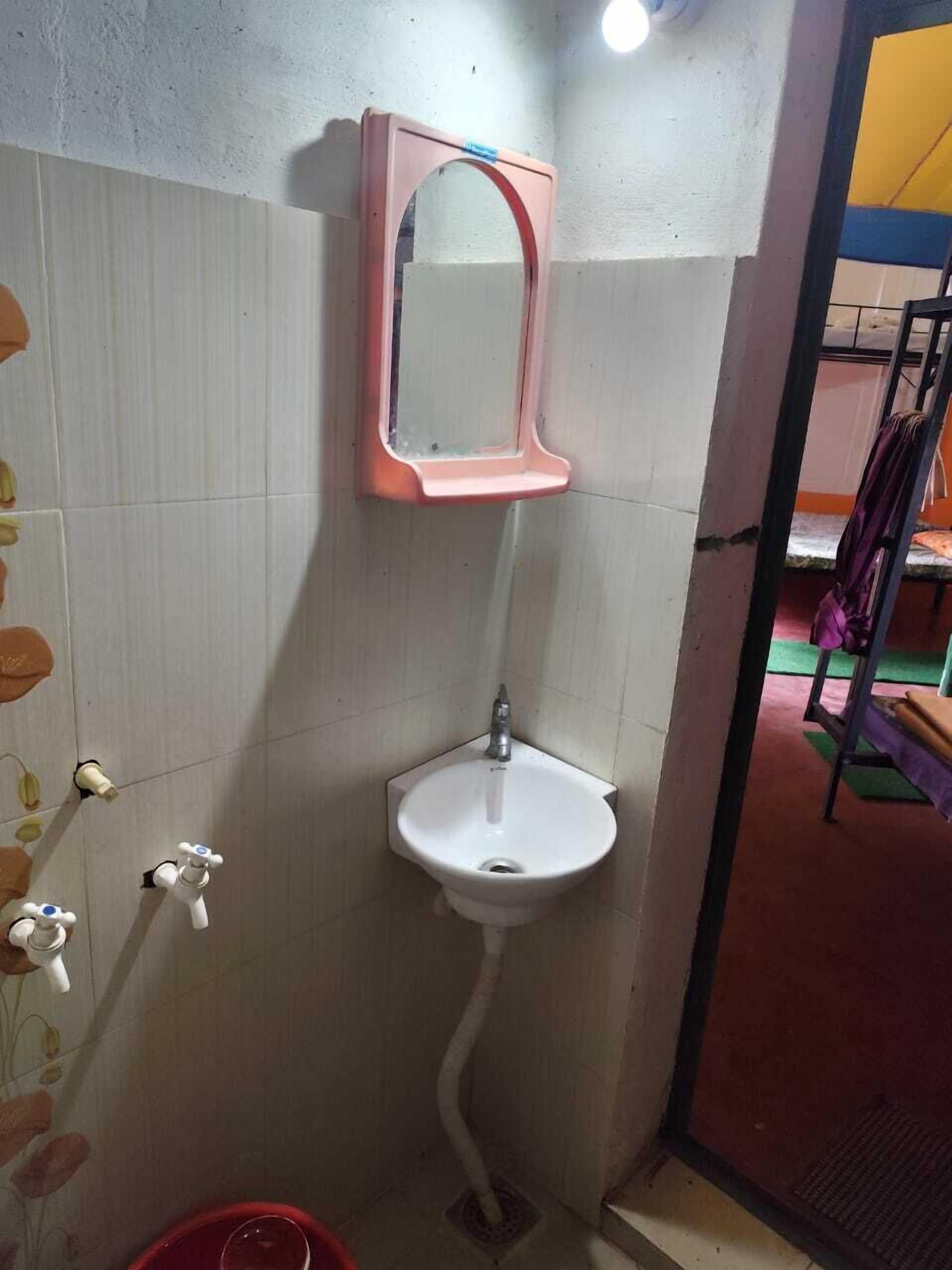 A bathroom with a white sink, a mirror, and a red bucket.
