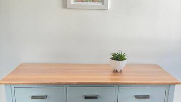 Een lichtblauwe dressoir met zes lades en een houten bovenblad. Daarboven hangt een lijst met een landschap.