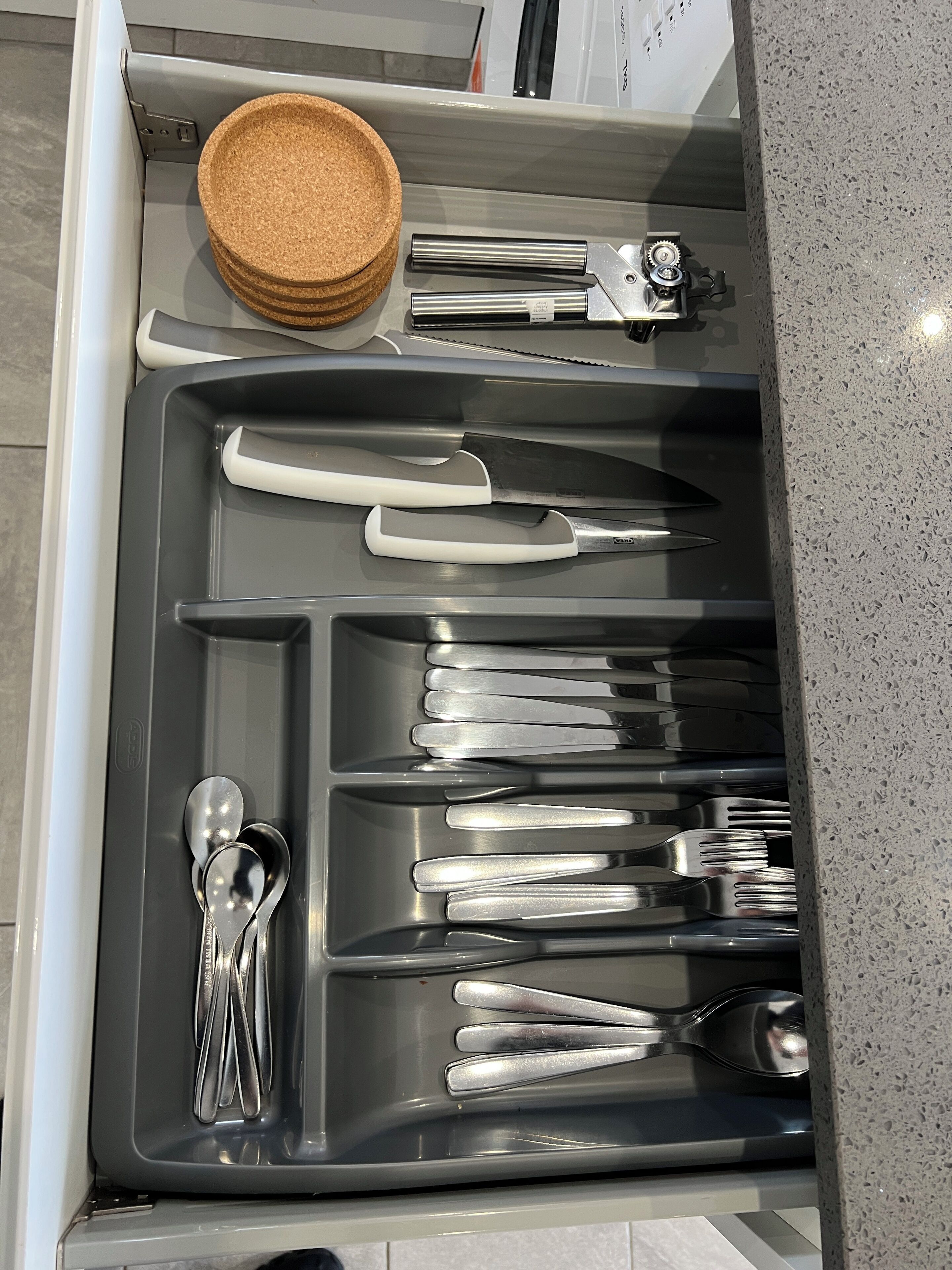 Een keukublade met keukengerei en een kurken mat.