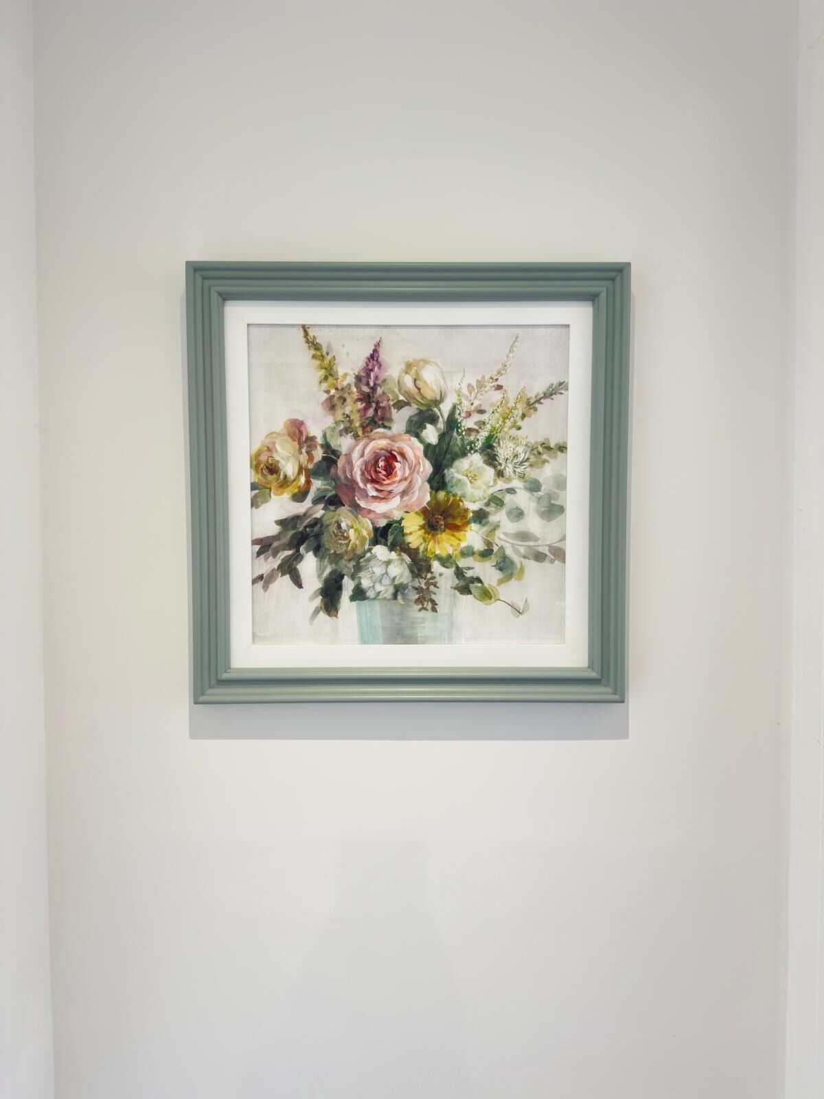 Ein gerahmtes Blumenbild an einer schlichten Wand.
