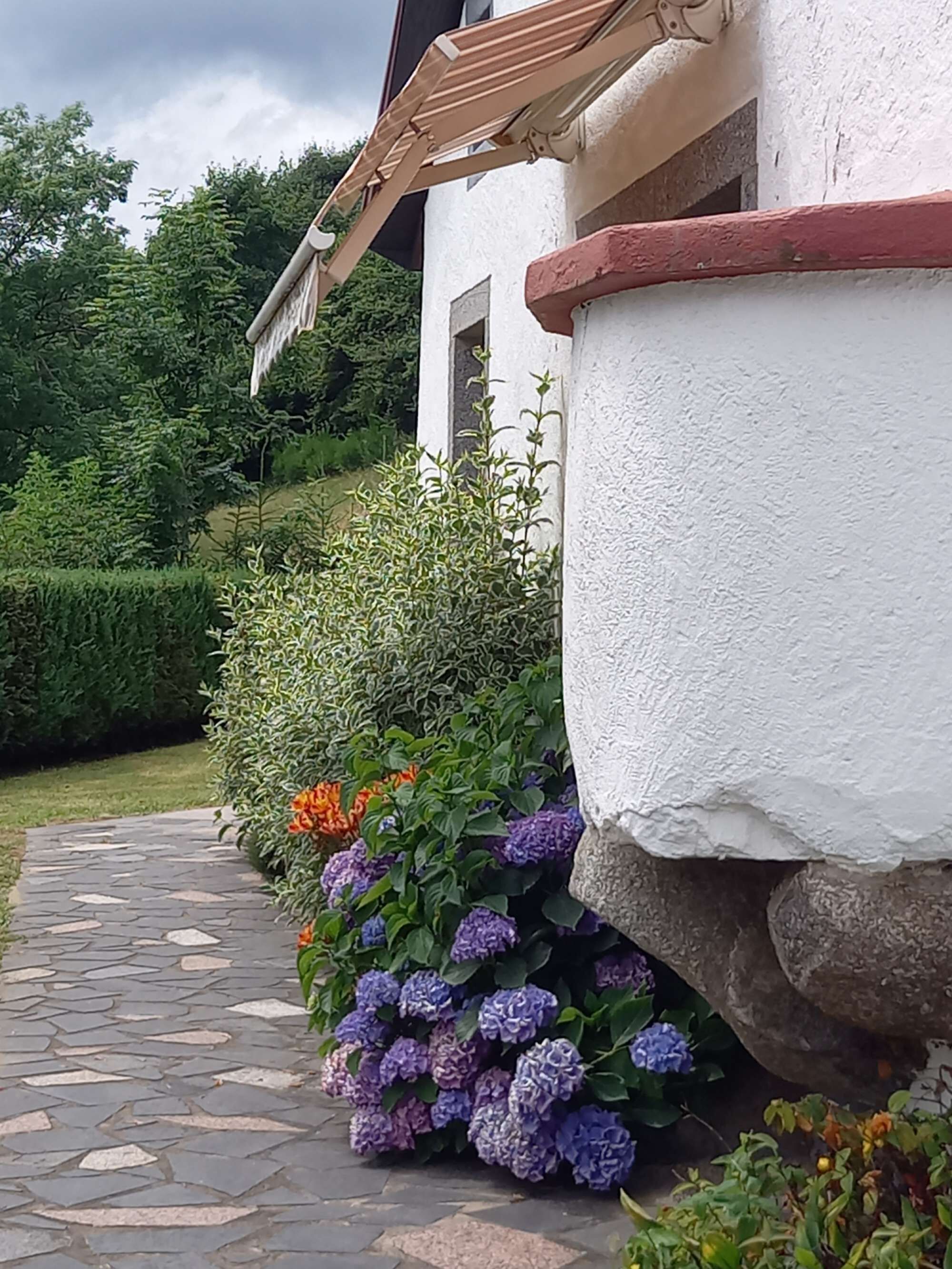 Un chemin de pierres mène à un bâtiment blanc surmonté d’un toit rouge.