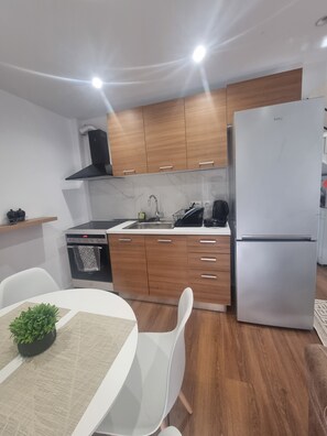 Une cuisine moderne avec des meubles en bois, un réfrigérateur en acier inoxydable et un four encastré.