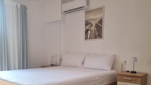 A modern bedroom with a wooden bed, a nightstand, a bedside table, and a wall-mounted air conditioner. - Stylish 1 Bedroom Duplex Apartment (Tiranë)