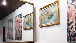 A lobby with two black leather chairs, a glass coffee table with magazines, a radiator, and framed paintings on the walls. - Hotel Al Porto (Imperia)