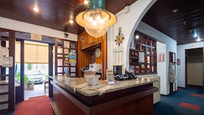 A reception area with a wooden counter, a clock, and a telephone. - Hotel Al Porto (Imperia)