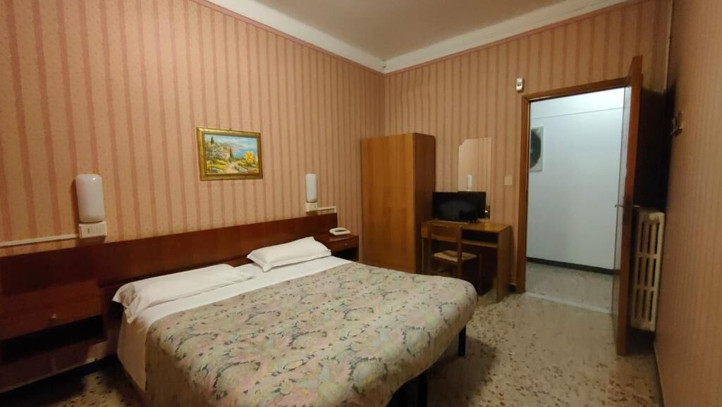 Une chambre d’hôtel équipée d’un lit, d’un bureau, d’une télévision et d’une armoire.