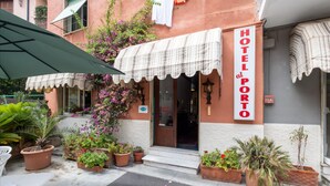 Un hotel chiamato "HOTEL PORT" con tenda a quadri, piante in vaso e un ingresso ben visibile.