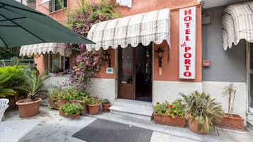 A hotel named "HOTEL PORT" with a checkered awning, potted plants, and a visible entrance.