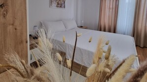 Une chambre à coucher comprenant un lit, un appareil de climatisation, une table de chevet et une fenêtre avec des rideaux.