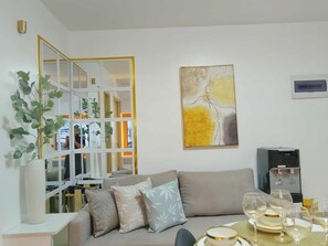 A modern living room with a sofa, decorative pillows, a coffee table with glasses, a water dispenser, and a framed abstract painting. - 2-bedroom Condo In Centro Spatial at the Heart of Davao City-Fully-Furnished (Davao City)