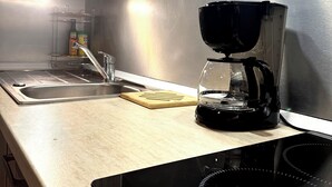 A modern kitchen with a built-in stove, a coffee maker, and a knife block on the counter. - Coconut Lodge - Marina des Trois-ilets-T1 (Les Trois-Îlets)