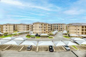 Un edificio residencial de varios pisos con zona de estacionamiento y espacios de estacionamiento cubiertos.