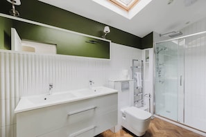 A modern bathroom with a skylight, a glass shower enclosure, and a white vanity with a sink.