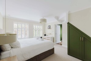 A bedroom with a bed, bedside lamp, dresser, and a green wardrobe.